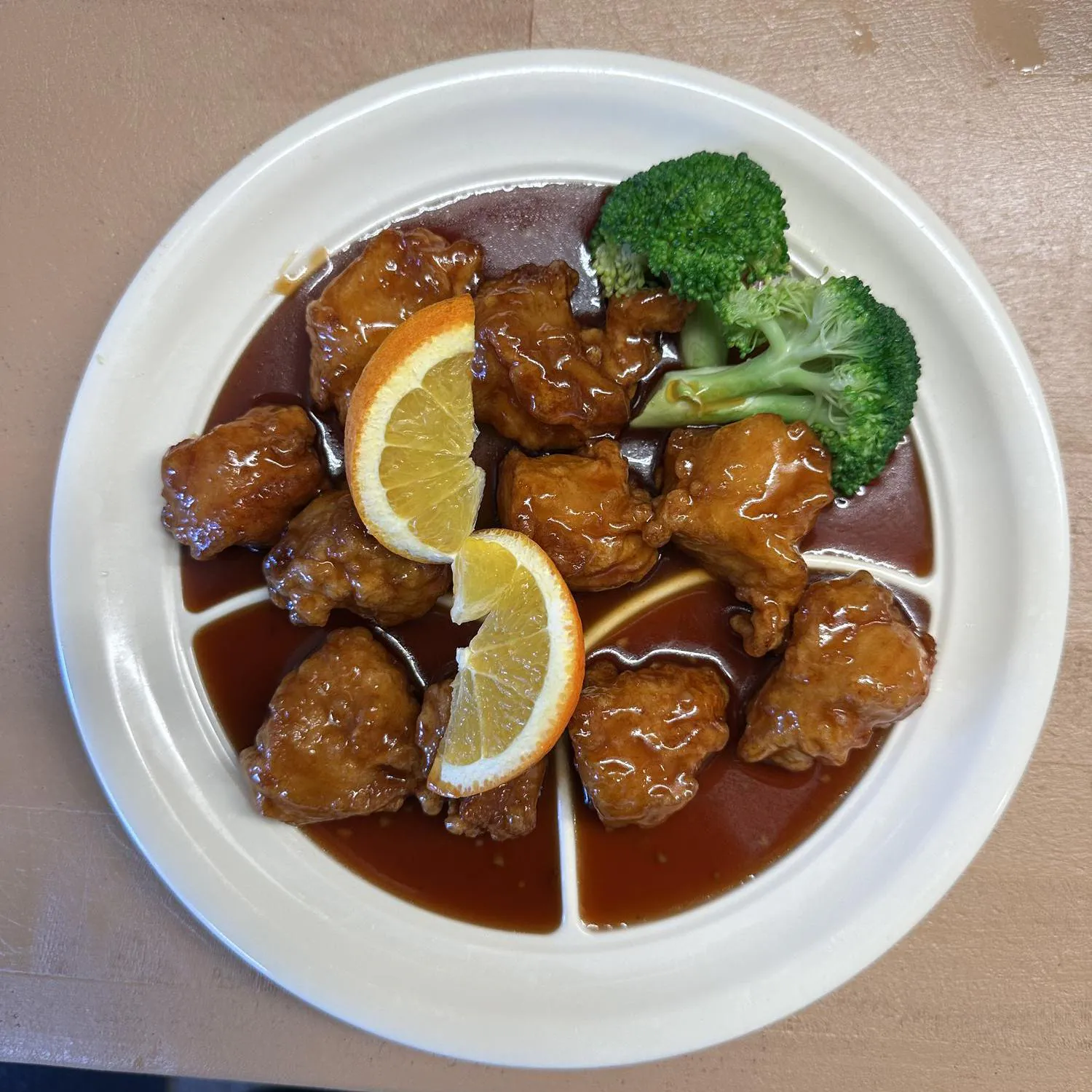 Orange Chicken presents crispy chicken pieces coated in an orange - flavored sauce, garnished with orange slices and broccoliat Asian Wok, a Chinese restaurant in Port Lavaca